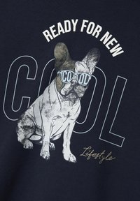 Camiseta de color azul marino con un gráfico de un Bulldog Francés usando gafas de sol y el texto "LISTO PARA LO NUEVO Y COOL" en una fuente atrevida.