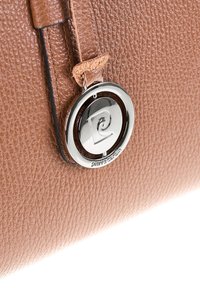 Gros plan sur un sac en cuir marron texturé avec un fermoir circulaire en métal argenté arborant un logo en spirale et le texte en relief "Pierre Cardin."