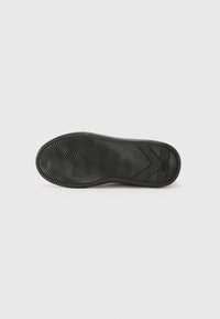 Suola di scarpa in gomma nera con una texture ondulata e un motivo di battistrada prominente. Presenta un design stampato con un logo in rilievo sul lato.
