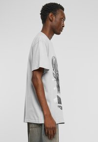 Gray cotton T-shirt featuring a prominent graphic on the front, round neckline, and short sleeves. Relaxed fit with a straight hem.