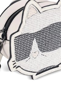 Mała torebka w kształcie kociej twarzy, z teksturowanej białej tkaniny z czarnymi akcentami, zdobiona kamieniami ozdobnymi oraz z podwójnymi zamkami błyskawicznymi.