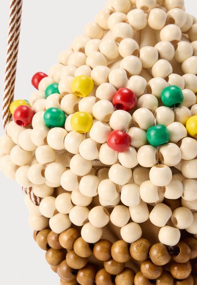 Συστάδα ξύλινων χαντρών σε φυσικά, κόκκινα, πράσινα, κίτρινα και καφέ χρώματα, περασμένα στενά στη σειρά πάνω σε υφασμάτινη επιφάνεια.