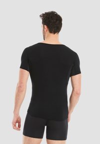 Black short-sleeve t-shirt with a round neck and fitted design, made of smooth fabric, showing a seamless back and side panels for flexibility.