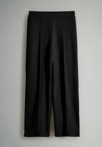 Zwarte wijde broek met een gladde textuur, voorzien van een tailleband en voorplooien. Zijkanten zijn voorzien van een contrasterende witte streep.