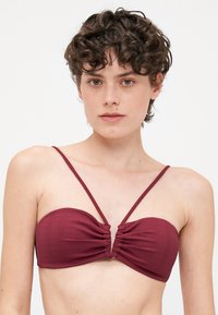 Bordeaux ribbet bandeaubit med samlet midtdetalj og tynne justerbare stropper. Glatt tekstur, minimalistisk design.