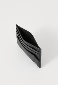 Black leather cardholder with textured front, multiple slots for cards, and a smooth interior. Compact design, minimalist aesthetic.