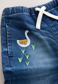 Denimshorts med elastik i taljen og kremfarvet snøre, med hvide og gule broderede gæs og grønne græsdetaljer.
