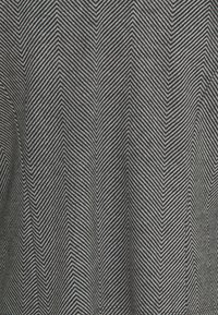 Svartvit fiskbensväv med tunna, diagonala ränder. Slät textur med en strukturerad finish som skapar ett distinkt mönster.