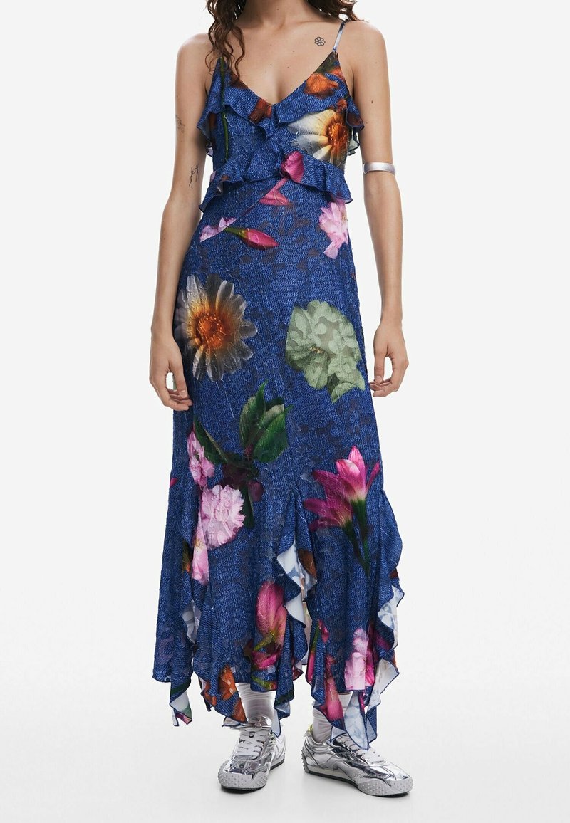 Pitkä maksimekko kukkakuviolla, jossa on röyhelöhihnat, sininen farkkumainen tekstuuri ja eloisat vaaleanpunaiset ja keltaiset kukat, sekä kellotettu helma.