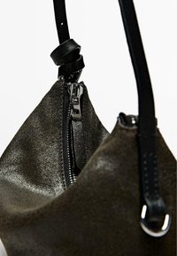 Borsa in pelle verde scuro con una finitura testurizzata, dotata di una zip argento e una tracolla nera ad anello per il trasporto.
