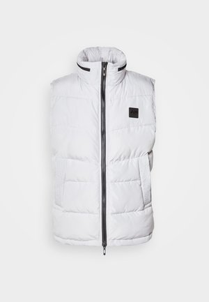 Hvid puffer vest med høj krave, lynlås foran og sidelommer. Har quiltet tekstur og et mærke på brystet.