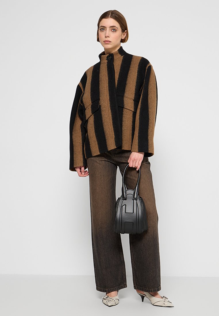 Braun und schwarz gestreifte, übergroße Wolljacke mit hohem Kragen, zwei frontalen Taschen, kombiniert mit dunklen Jeans und einer kleinen schwarzen Tasche.