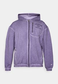Violets zip-up džemis, kas izgatavots no mīksta auduma, ar priekšējo kabatu, ribotām aprocēm un izšūtu "Champion" logo uz krūšu.
