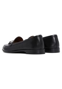 Black leather loafers with a rounded toe, low heel, and decorative buckle detail on the front. Smooth texture and sleek design.