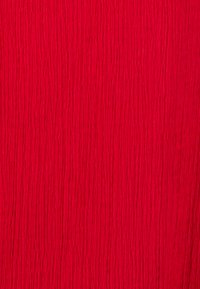 Tessuto rosso con una superficie grinza, caratterizzato da linee verticali, che conferisce un aspetto vibrante e dinamico.