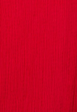 Tejido rojo texturizado con una superficie arrugada, que presenta líneas verticales, proporcionando una apariencia vibrante y dinámica.