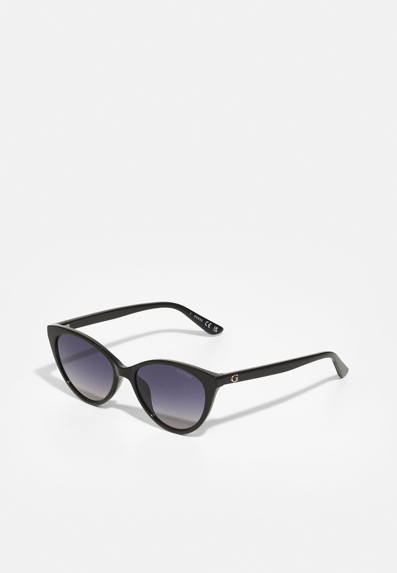 Lunettes de soleil noires en forme d'œil de chat avec lentilles dégradées, monture en acétate lisse et accent logo métallique sur les tempes.