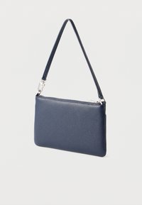 Temno modra usnjena torbica z teksturirano površino, z zadrgo in odstranljivo zapestno trakovo. Kompaktna pravokotna oblika.