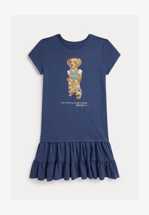 Robe bleu marine à manches courtes avec ourlet volanté, ornée d’un motif d’ours portant un gilet en laine et un pantalon raccommodé, avec le texte « Polo Bear by Ralph Lauren ».