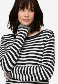 Maglione a maniche lunghe a righe blu navy e bianche con scollatura ampia e polsini a costine. Il tessuto appare morbido con una vestibilità comoda.