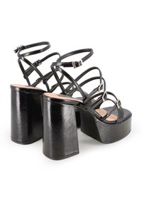 Sandalias de tacón alto negras con múltiples correas ajustables y un tacón grueso y cuadrado. Material suave y brillante con una base de plataforma.