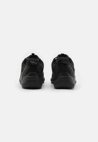 Schwarze Sportschuhe zeichnen sich durch ein strukturiertes Obermaterial, einen gepolsterten Schaft und eine robuste Sohle mit Traktionsdetails aus. Minimalistisches Design mit dezenten Branding.
