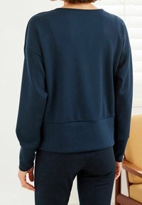 Sweat-shirt bleu marine à manches longues et coupe décontractée, doté d'un col arrondi et de poignets côtelés, accompagné d'un pantalon assorti.