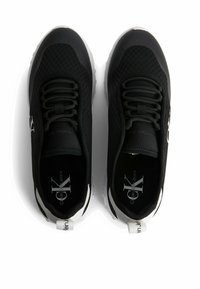 Svarta nät-sneakers med texturerad yta, med en vit accent-sula och varumärke på sidorna. Snörningsdesign med dragflikar.