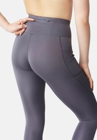 Hoog-getailleerde, strakke leggings van een gladde, rekbare grijze stof, met een achterzak en subtiele stikdetails.