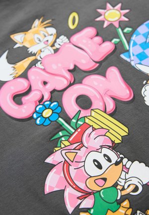 Graphic T-shirt featuring a dark gray background with colorful cartoon characters and the text "GAME ON" in pink bubble letters.