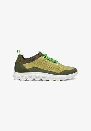 Zapatillas deportivas verdes y beige hechas de malla y materiales sintéticos, con una parte superior texturizada, cordones elásticos y una suela blanca con ranuras.