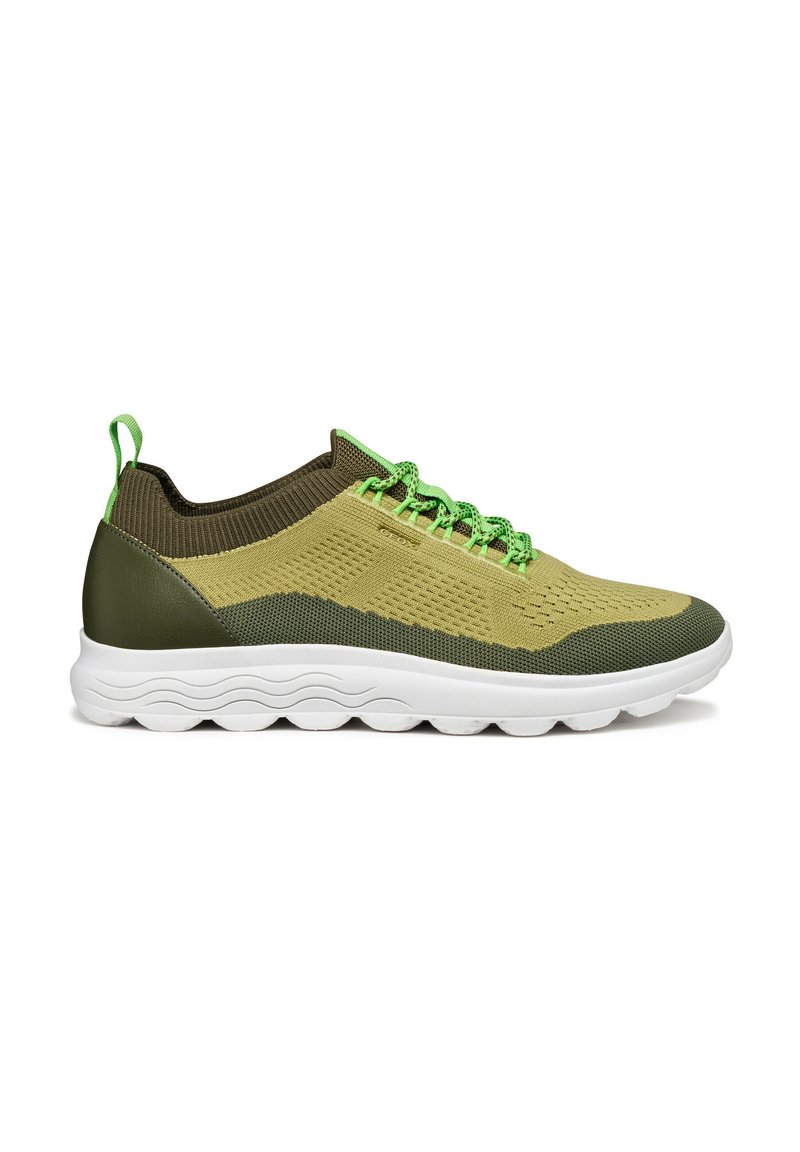 Zapatillas deportivas verdes y beige hechas de malla y materiales sintéticos, con una parte superior texturizada, cordones elásticos y una suela blanca con ranuras.