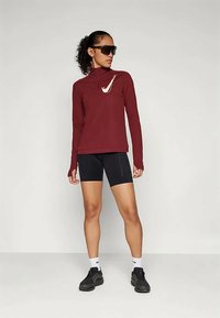 Bordoo pika pikka varrukatega särk kõrge kaelusega ja valge logoga, koos mustade rattapükstega. Mustad tossud valgete aktsentidega lõpetavad komplekti.