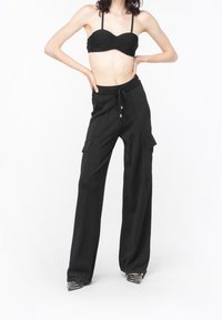 Zwarte cargobroek met een trekkoord in de taille, brede pijpen, twee zijzakken en een subtiele glans, gecombineerd met een zwarte strapless crop top.