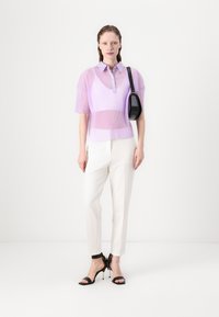 Lys lilla ribbet kortermet polo skjorte med knapper; kombinert med hvite slanke bukser og svarte høye sandaler med stropper.