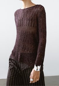 Pull en maille violet avec un décolleté large, des manches longues et un motif texturé. Les poignets sont ornés d'un accent métallique argenté.