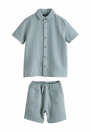 Svetlomodrá, textúrovaná košeľa s krátkym rukávom a gombíkmi, v kombinácii so zodpovedajúcimi elastickými šortkami s šnúrkou a prednými vreckami.
