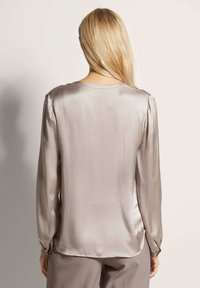 Zijdeachtige, licht taupe blouse met lange mouwen, een ronde halslijn en geplooide schouders, met knopen bij de mouwen en een gladde textuur.