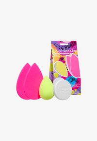 Jasnoróżowe i żółte gąbki do makijażu z białym mydłem do czyszczenia oraz kolorowym opakowaniem Beautyblender Cleantemporary Trio.