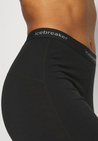 Fekete leggings, széles derékpánttal, amelyen az "icebreaker" márkajelzés található. Simaságuk és feszes illeszkedésük kényelmet biztosít.