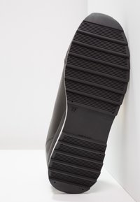 Black rubber shoe sole with horizontal grooves and a rounded edge. Features embossed size marking '37' and 'MADE IN ITALY.' Smooth texture.