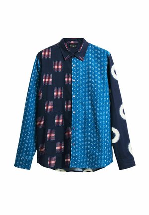 Chemise à manches longues à boutons avec motifs bleus mélangés : bleu foncé avec des carrés rouge-blanc, bleu vif avec de petits traits blancs, et bleu marine avec des cercles blancs.