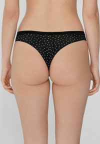 Schwarze Bikini-Höschen mit weißen Punkten, ausgestattet mit einem weichen, elastischen Bund und einer glatten, dehnbaren Textur.