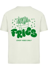 Lichtgekleurde t-shirt met een groene afbeelding van frietjes in een verpakking, met het woord "FRIES" en de tekst "CRISP VIBES ONLY" eronder.