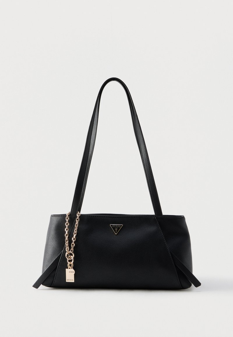 Sac à main Guess en cuir noir avec deux longues sangles, logo triangulaire et chaîne dorée avec étiquette de marque sur fond uni.