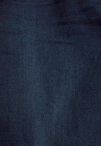 Tela de mezclilla azul oscuro con una textura suave y un sutil patrón de tejido diagonal, que presenta ligeras variaciones en el tono a lo largo de toda la superficie.