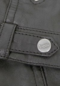 Schwarzes Leder mit strukturiertem Oberflächen, ausgestattet mit einem silbernen Metallknopf mit der Gravur "Mauritius" und kontrastierenden schwarzen Nähten.