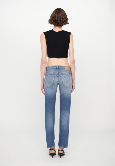 Black cropped top with scalloped edges, paired with light blue, straight-leg denim jeans featuring back pockets and a subtle fade.