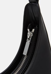 Sort lædertaske med en glat tekstur, der har en sølvfarvet lynlås og træksnor. Designet er strømlinet med en buet form.