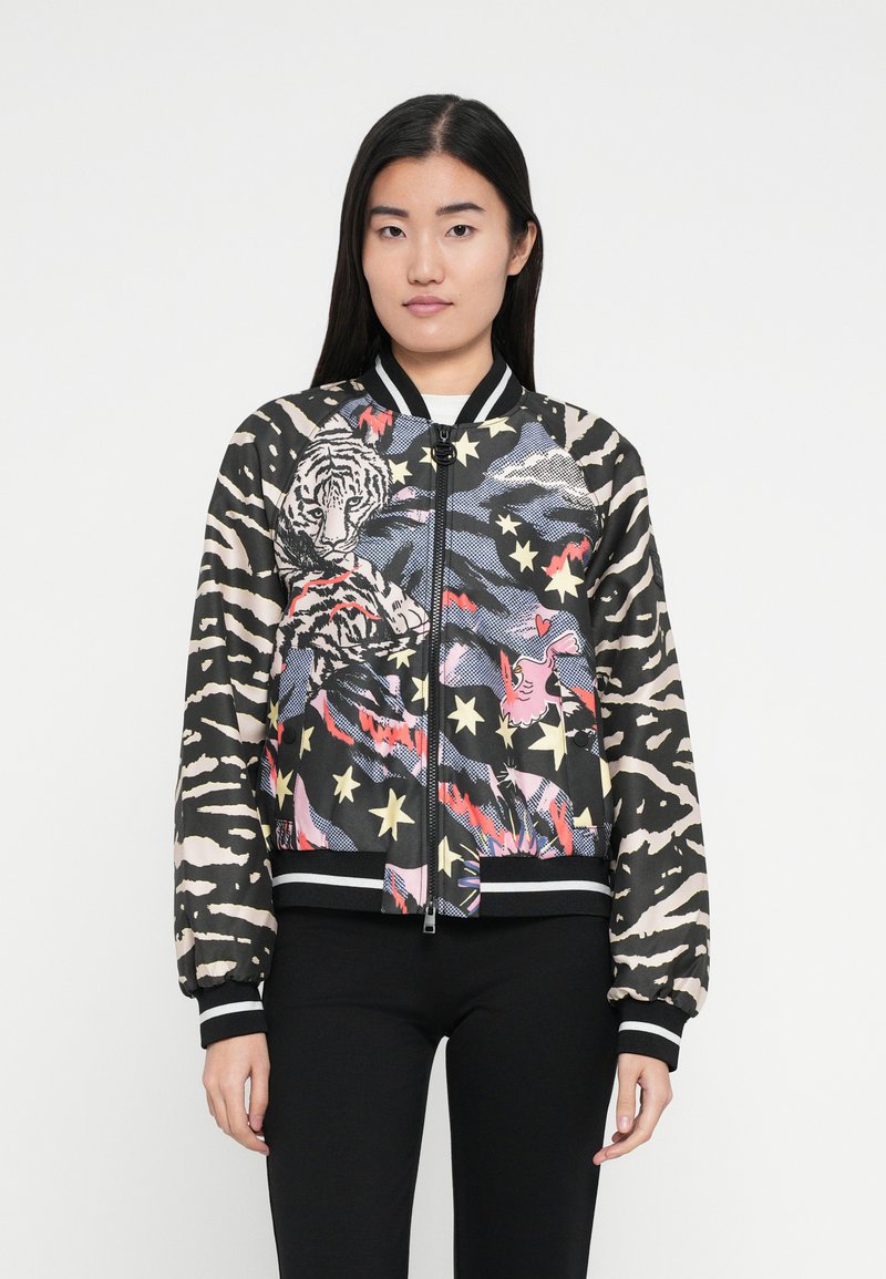Chaqueta bomber negra con estampado de tigre y estrellas, con un patrón de rayas en las mangas y puños y dobladillo acanalados. Cierre de cremallera.